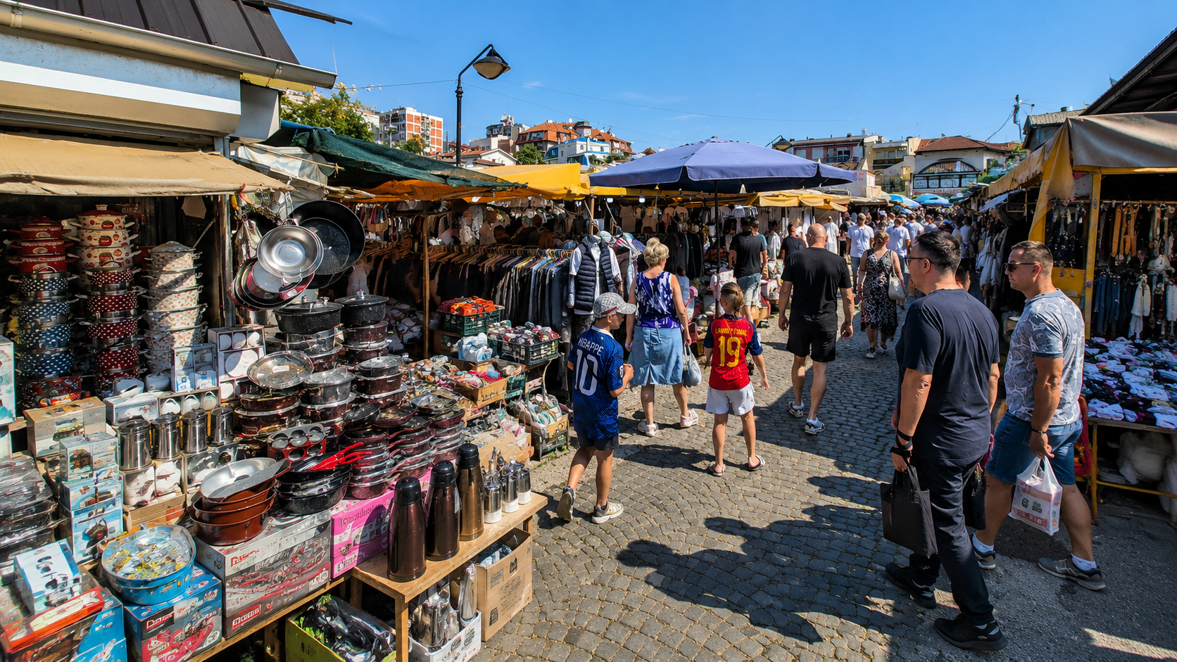 Natkriven prolaz sa tezgama posuđa, termosa i garderobe na robnoj pijaci